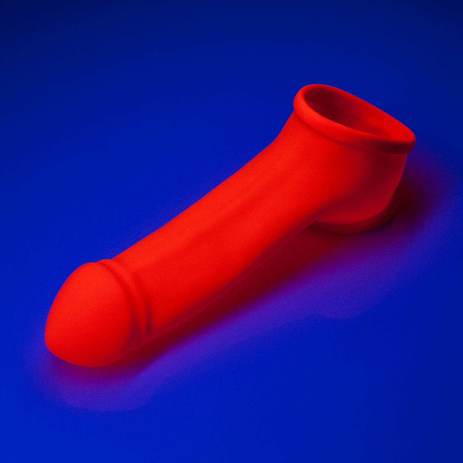 Toylie Latex Penis Sleeve «ERIK» neon orange (glow effect), with molded glans and testicle ring